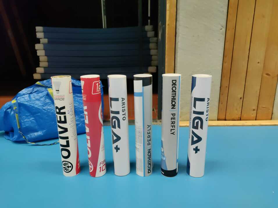 Reihe von verschiedenen Sportartikeln auf einem Tisch, mit Marken wie OLIVER und Decathlon sichtbar.