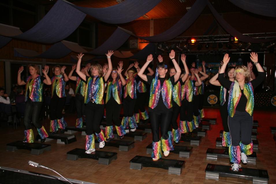 Gruppe von T&auml;nzerinnen in bunten Kost&uuml;men, die auf Steppbrettern in einem festlich dekorierten Raum tanzen.