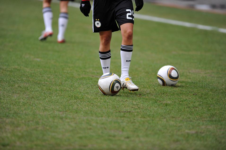 Nahaufnahme eines Fußballspielers mit einem Ball auf dem Rasen, im Hintergrund ein weiterer Ball.